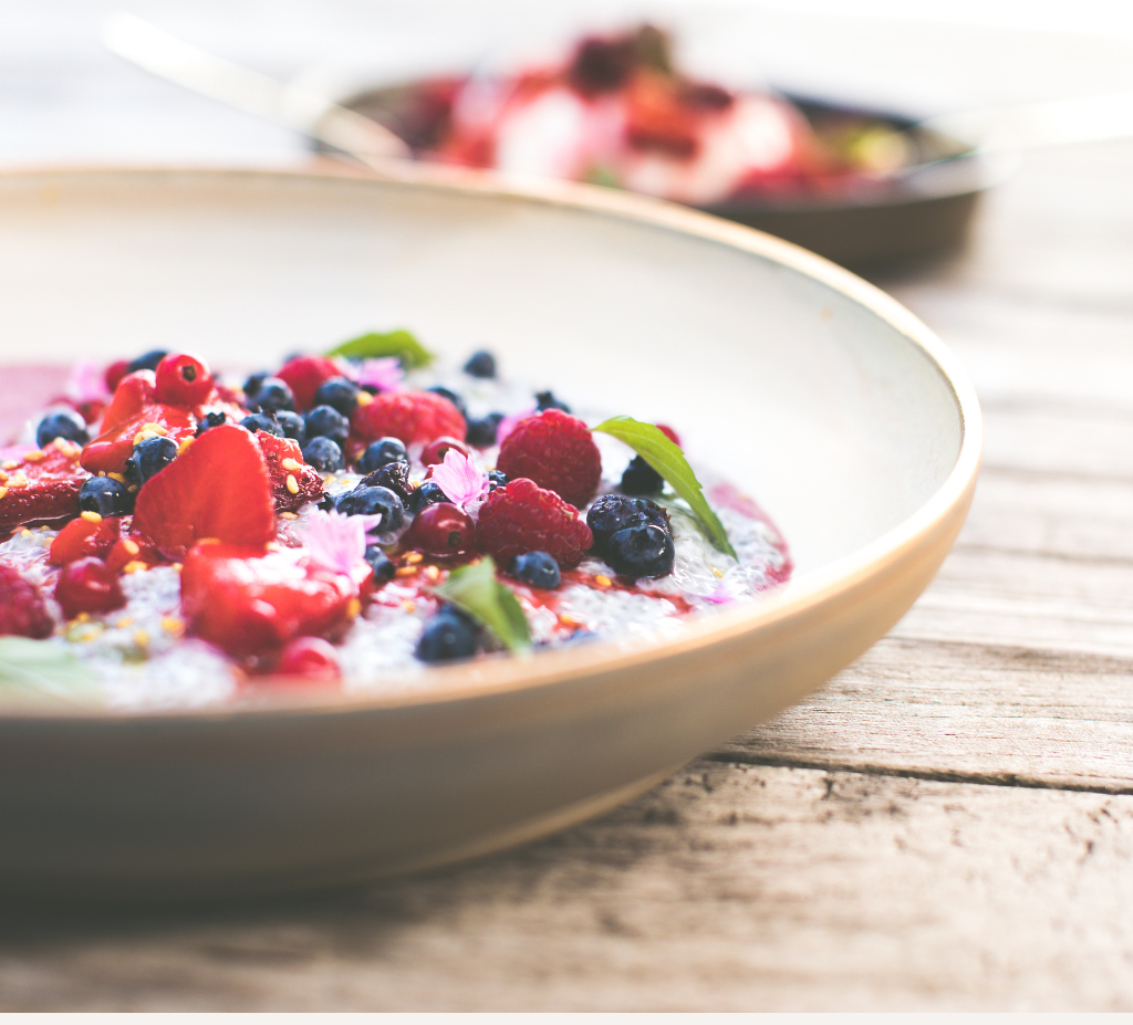bowl of fertility nutrients including chia pudding with blueberries, raspberries, mint and strawberries.